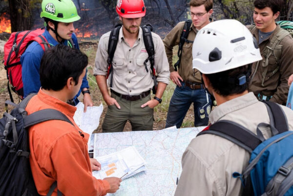 Group of conservationists in safety gear discussing a prescribed fire plan on-site