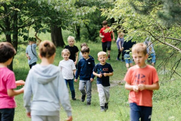 Group of children exploring a forest during a nature school activity, highlighting outdoor education